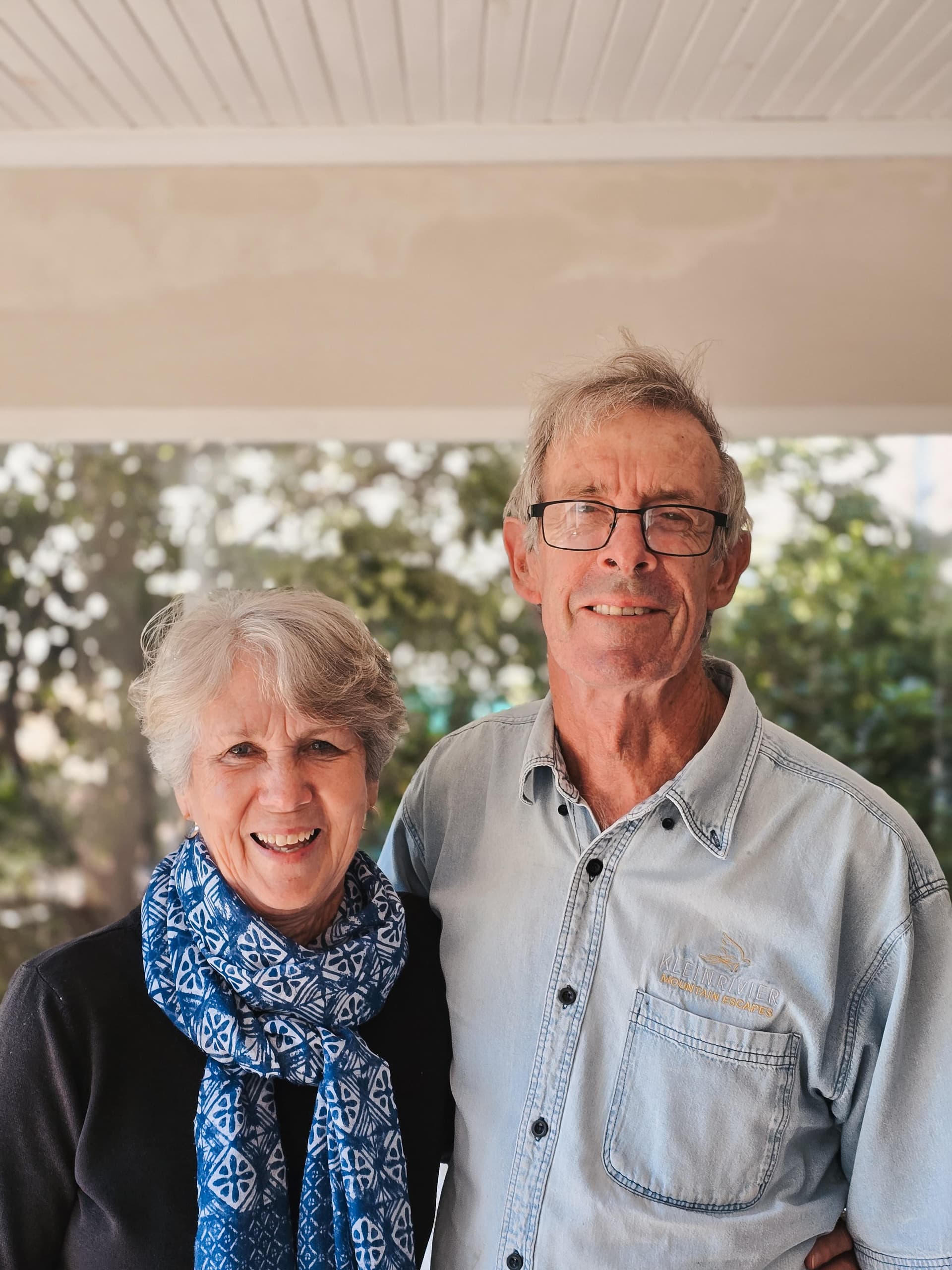 Jen and Brad Sharp, owners of Pebbles Beach Cottage, smiling together outdoors.